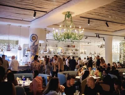 Gallery 7/40 Dubai, lively dining atmosphere with chandeliers and patrons.