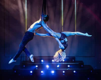 Aerial performers at DREAM Dubai Dinner Show, vibrant stage lighting.
