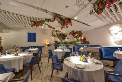 Elegant dining area with blue chairs and floral decor at Opa Dubai.