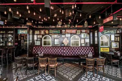 Vintage-style pub interior with leather seating and framed memorabilia, Dubai.