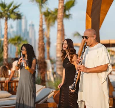 Musicians performing at Be Beach DXB, Dubai, with palm trees.