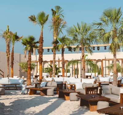 Palm trees and lounge seating at Be Beach DXB, Dubai.