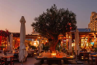 Outdoor dining area at Surf Club Dubai during sunset.