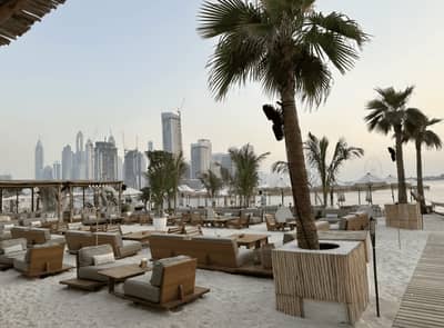 Beachfront seating at Surf Club Dubai with city skyline view.