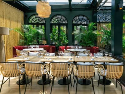 Elegant dining area at Eugène Eugène Restaurant, Dubai with lush greenery.