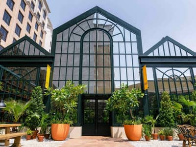 Eugène Eugène Restaurant Dubai entrance with glass facade and plants.