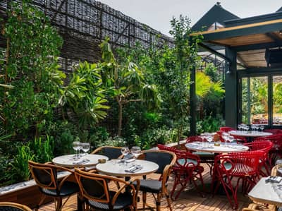 Eugène Eugène Restaurant Dubai outdoor seating with lush greenery.