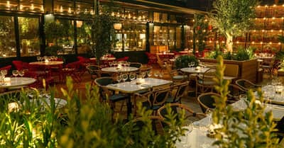 Outdoor dining at Eugène Eugène Dubai, illuminated with warm lighting.