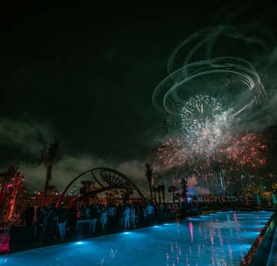 Fireworks over Be Beach DXB, Dubai, with poolside crowd.