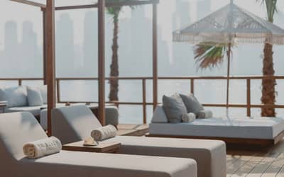 Lounge chairs at Be Beach DXB, Dubai, with city skyline view.