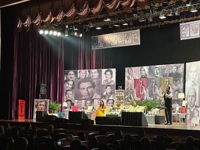 Stage performance at Sheikh Rashid Auditorium, Dubai with actors and portraits.