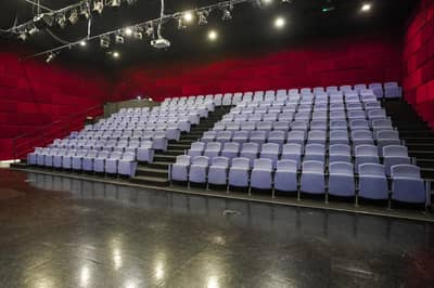 Empty theater seating at The Junction Dubai, red walls, overhead lights.