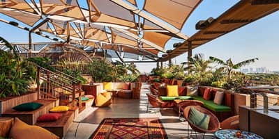 Colorful rooftop seating at Monkey Bar Dubai with city view.