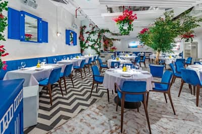 Elegant dining area at Opa Dubai with blue chairs and decor.