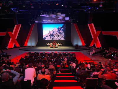 Audience at Expo Centre Sharjah conference with large screen display.