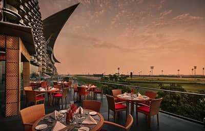 Outdoor dining at The Meydan Hotel terrace, Dubai, during sunset.