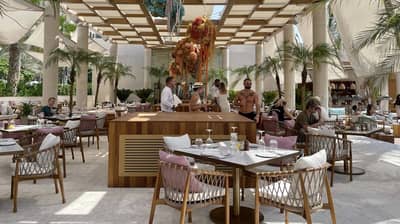 Outdoor dining area at Kyma Beach Dubai with palm trees.
