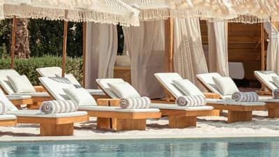 Kyma Beach Dubai sun loungers by poolside with cabanas.