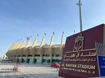 Al Nahyan Stadium exterior with flags, Abu Dhabi.