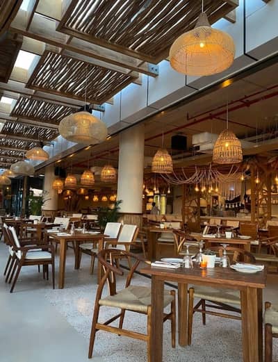 Ula Dubai Beach Club dining area with wooden tables and chairs.