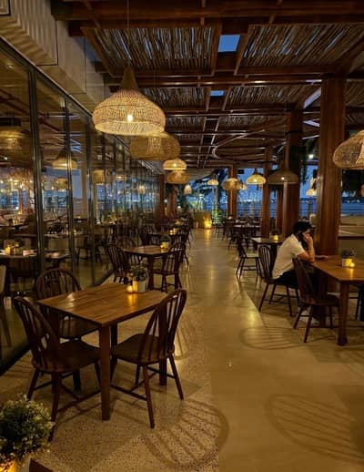 Ula Dubai Beach Club evening dining area with warm lighting.