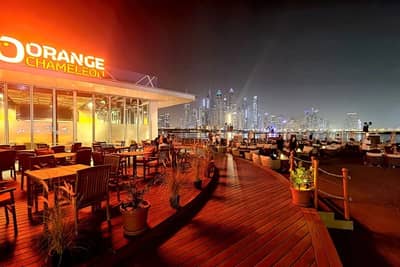 Orange Chameleon Restaurant Dubai, outdoor seating with city skyline view.