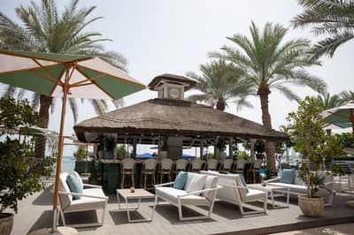 Outdoor seating at The Byron Bathers Beach Club, Dubai with palm trees.