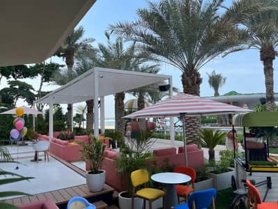 Outdoor seating at Peaches & Cream Beach Restaurant, Dubai with palm trees.