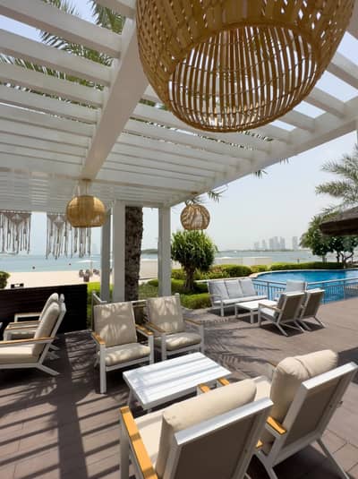 Outdoor seating at Cabana On The Beach Palm Dubai, overlooking ocean.