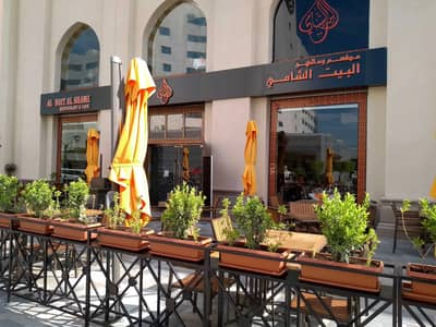 Al Bait Al Shami Restaurant outdoor seating, Dubai, with orange umbrellas.