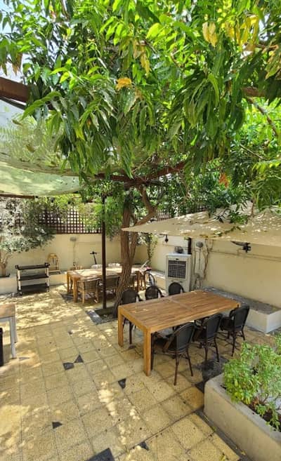 Outdoor seating area at Mamaesh Al Manara, Dubai, with wooden tables.