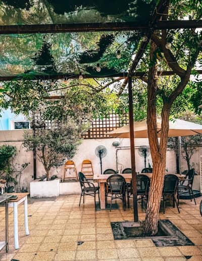 Outdoor seating at Mamaesh Al Manara, Dubai, with trees and fans.