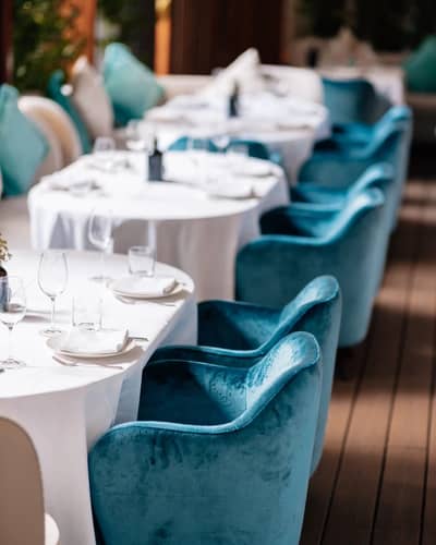 Elegant dining setup with blue chairs at Gaia Dubai restaurant.