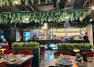 Charcoal Garden Restaurant Dubai, lush greenery, modern decor, dining tables.