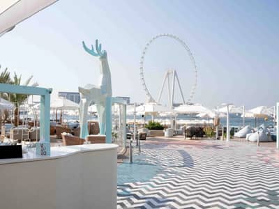 Yula Lounge Dubai, outdoor seating, geometric deer sculpture, Ferris wheel view.