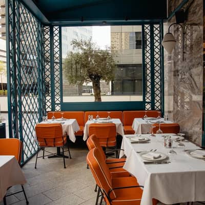 Outdoor dining area at Il Baretto Restaurant, Riyadh with orange chairs.