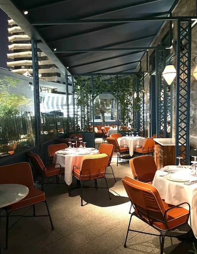 Outdoor dining area at Il Baretto Restaurant, Riyadh, with orange chairs.