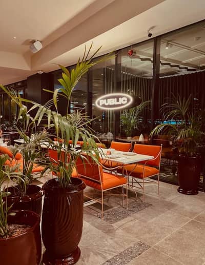 PUBLIC Restaurant Riyadh, elegant dining area with orange seating and plants.