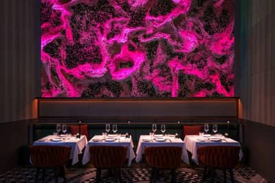 Elegant dining area with vibrant pink abstract wall, Zenon Restaurant Dubai.