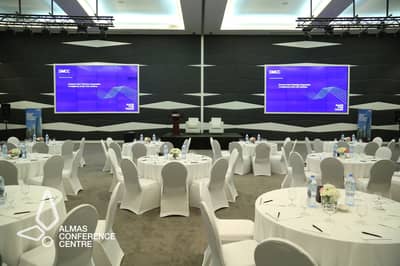Almas Conference Centre Dubai, round tables, stage with screens.