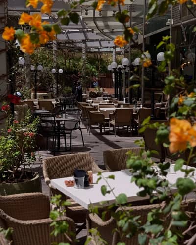 Outdoor seating at Twisted Olive & Naama’s Garden, Doha, with flowers.