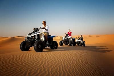 ATVs riding through Al Khatim Desert, Abu Dhabi under clear sky.