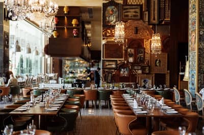 Elegant dining area at Tanatan Dubai with chandeliers and artwork.