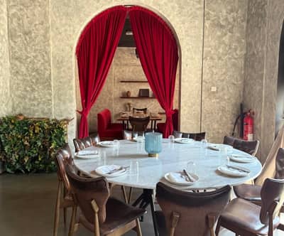 Elegant dining setup at 11 Woodfire Restaurant, Dubai with red curtains.
