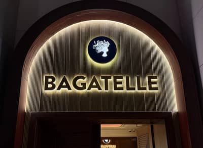 Entrance to Bagatelle Dubai, illuminated sign and logo.