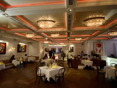 Elegant interior of Bagatelle Dubai with chandeliers and artwork.