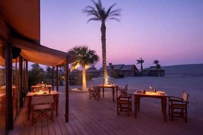 Outdoor dining area at The Outpost Al Barari, Doha, Qatar during sunset.