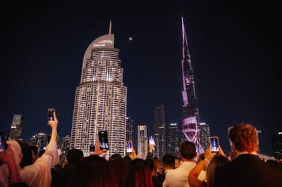 Crowd taking photos of illuminated skyscrapers at Nazcaa Japanese Peruvian Dubai, UAE.