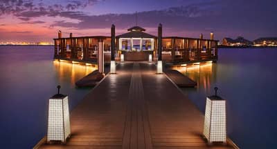 Illuminated pier at Banana Island Resort Doha By Anantara, Doha, Qatar during sunset.