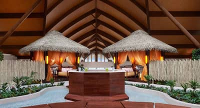 Thatched-roof cabanas and water feature at Banana Island Resort Doha By Anantara, Doha.